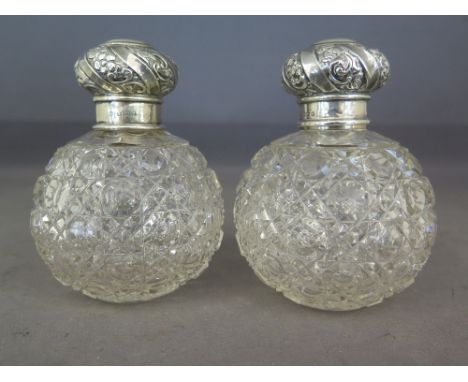 A pair of silver topped cut glass perfume bottles, foliate engraved silver hallmarked Birmingham 1904-05