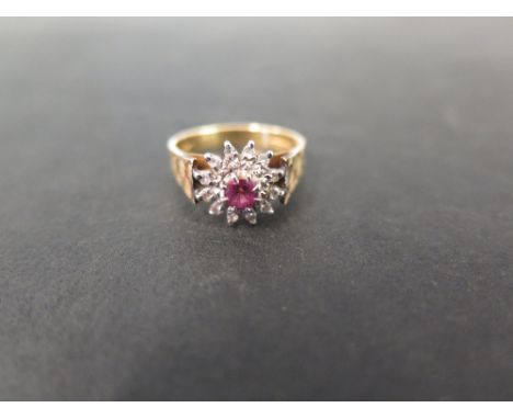 A 1970s 18ct gold ruby and diamond cluster ring - With textured shoulders - Hallmarked London - Ring size L 1/2 - Weight appr