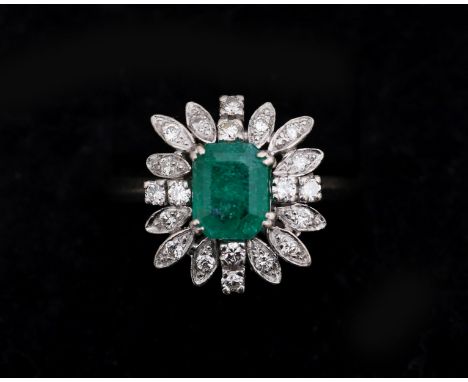 A 14 karat gold entourage ring, in flower shape, centrally set with an emerald cut emerald approx. 1.30ct. surrounded by an e