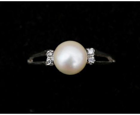 An 18 karat white gold ring, set with a cream/white 6.5/7 mm. cultured pearl, and on the shoulders on each jug two octagon cu