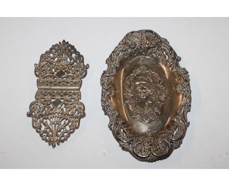 A pierced silver dish with portrait decoration of a female and an ornate silver plated buckle