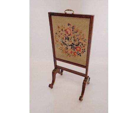 An early 19th century rosewood firescreen with vertical sliding tapestry panel, all on twin scroll supports and with brass in