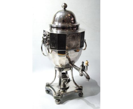 Silver tea urn of canted rectangular section with engraved panels, mask and ring handles on reeded supports and platform base