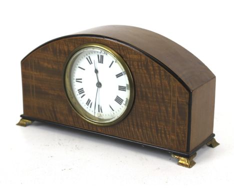 A 20th century mantel clock. The white enamel dial with Roman numerals, the mahogany case of domed form with inlaid details, 