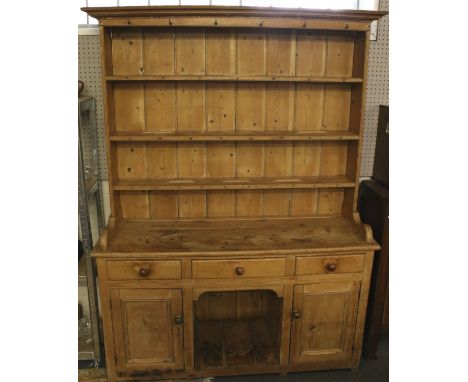 A vintage pine kitchen dresser. The upper section with three shelves, each with plate racks, the lower section with a long ce