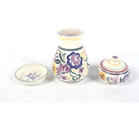 Three pieces of Poole pottery. Comprising a lidded pot, circular dish and a vase, all decorated with flowers on a cream groun