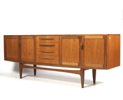 A mid-century G Plan (red label) teak sideboard. With four drawers to the centre flanked by two-door cupboards, on square tap