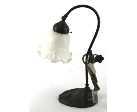 An Art Nouveau lamp, circa 1910, the bronze stand modelled as foliage, the glass shade with a fluted edge. H41cm