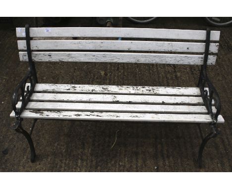 A wooden garden bench. The planks painted white, the cast metal ends painted black, H70cm x W125cm x D55cm