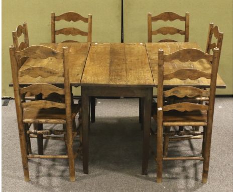 A vintage oak drop leaf table and a set of six ladder back chairs. The plank top table of rectangular form, raised on tapered