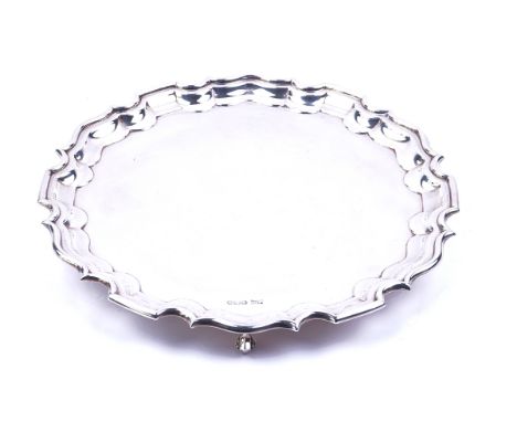 A SILVER SALVEROf shaped circular form, having a pie-crust rim in the Chippendale style, raised on three scrolled feet, diame