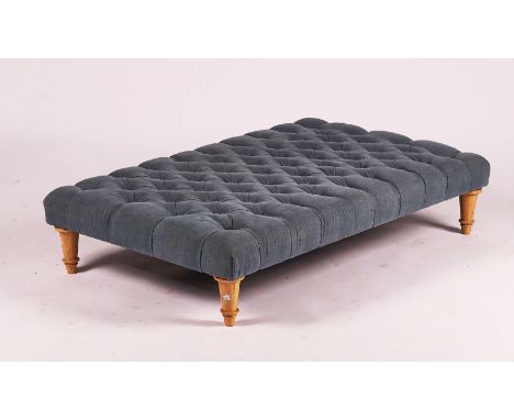 A LARGE MODERN RECTANGULAR FOOT STOOLWith button upholstered top on tapering turned supports, 130cm wide; 29cm high