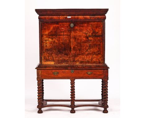AN EARLY 18TH CENTURY FIGURED WALNUT AND FEATHER BANDED ESCRITOIRE ON STANDThe cushion drawer over fall front revealing a fit