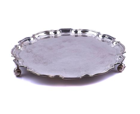 A SILVER SALVER OF SHAPED CIRCULAR FORMHaving a Chippendale style pie crust rim, raised on three scrolled feet, diameter 25.5