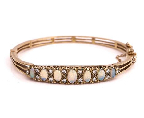 A 9CT GOLD, OPAL AND DIAMOND OVAL HINGED BANGLEMounted with a row of seven graduated oval opals and with pairs of circular cu