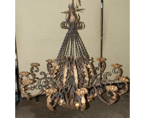 A wrought iron twelve light chandelier, with scrolling branches and gilt foliate decoration, 140cm drop x 140cm diameter