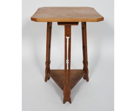 A Liberty style oak occasional table, the canted square top on a pierced tripod base with shelf stretcher, 74cm high x top 48