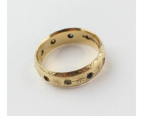 A yellow metal 5.50mm wedding ring set with blue and white synthetic spinels. Hallmarked 9ct gold. Date letter for 1971. Size