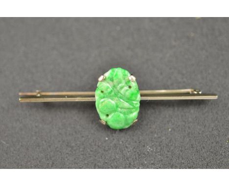 A platinum bar brooch, mounted with jade with carved and pierced foliate decoration - L 5.5cm. CONDITION REPORT: Good conditi