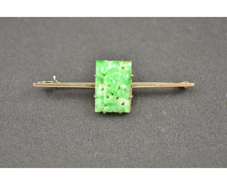 A 9ct white gold bar brooch, mounted with jade with carved and pierced flower detail - L 6cm. CONDITION REPORT: Good conditio