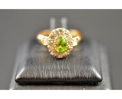 A yellow metal ring with central peridot surrounded by twelve diamonds, and diamond set shoulders - size M 1/2. CONDITION REP
