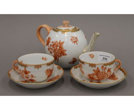 A Herend porcelain teapot and two cups and saucers. The teapot 20 cm long.