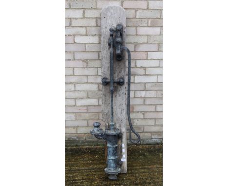 A vintage cast iron pump mounted on a wooden board. 152 cm high overall.