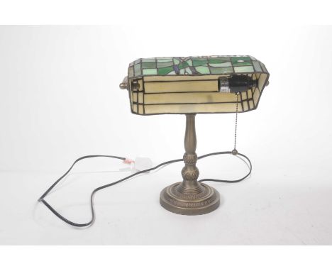 A Tiffany style desk lamp Mounted on a brass bracket and knopped stand, spreading from a circular base, the shade depicting a