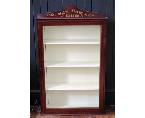 An Edwardian mahogany glazed wall display cabinet for Holman, Ham &amp; Co, Exeter, of arched outline. with glazed panelled d