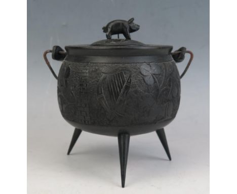 An Irish bog oak carved miniature swing-handled cauldron and cover, of circular form, the cover surmounted by a piglet, the b