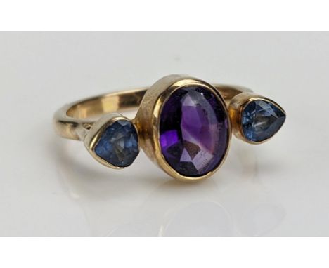 A Cabochon Amethyst and Blue Stone Ring, rub over set and in an unmarked precious yellow metal setting, tests as 10ct on KEE,