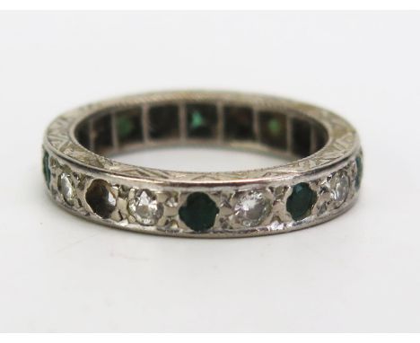 An Emerald and Diamond Eternity Ring in an unmarked precious white metal setting, size J, c. 3.91g. One emerald missing 