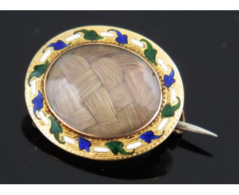 A Georgian Gold and Enamel Oval Memorial Brooch with a central glazed panel set with woven hair, KEE tested as 15ct, 17x14.5m