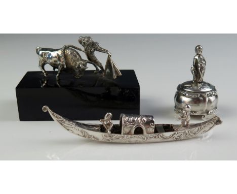 A continental miniature silver model of a bullfighter and bull, mounted on a rectangular base, a silver model of a gondola, a