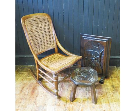 An elm and oak rocking chair with cane panel back and seat, an oak footstool and a carved oak fire screen. (3). 
