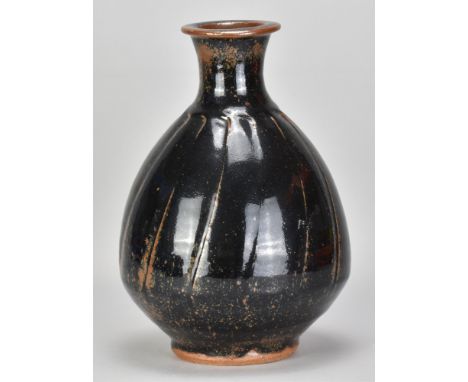 JIM MALONE (born 1946); a large bulbous faceted stoneware bottle covered in tenmoku breaking to kaki glaze, impressed JM and 