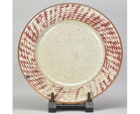 DAVID LLOYD JONES (1928-1994); a stoneware charger/wall hanging covered in speckled grey glaze with copper red rim and wax re