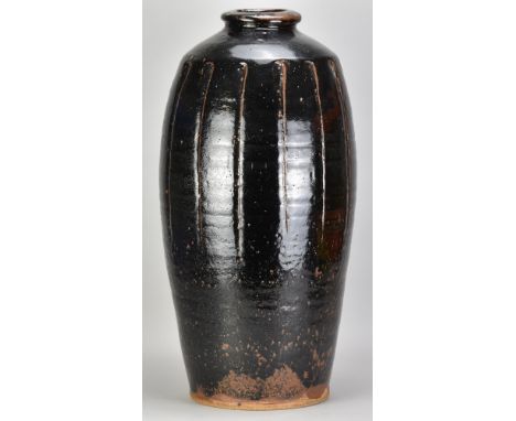 JIM MALONE (born 1946); a very tall fluted stoneware bottle covered in tenmoku breaking to kaki glaze, impressed JM and A (fo