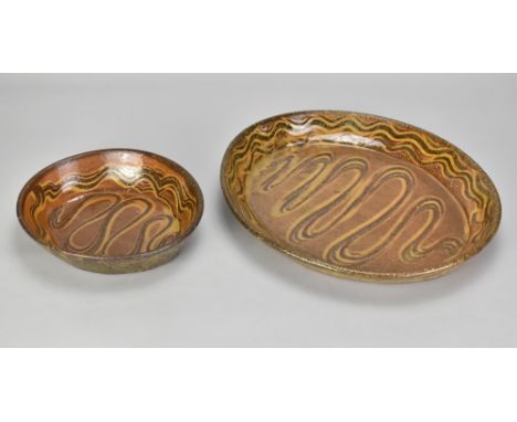 Winchcombe Pottery; a large early oval slipware dish with meander decoration, diameter 34cm, and a smaller example, diameter 