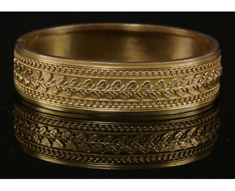 A Victorian gold flat section hinged Etruscan-style bangle, c.1870,17mm wide.  Decoration to the top half with a central row 