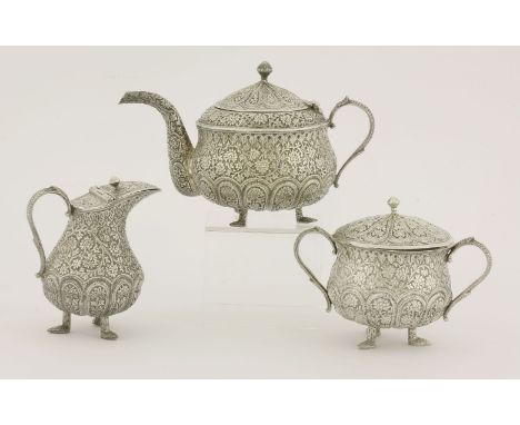 An Indian white metal tea set,c.1930,richly cast with flowering scrolls and lunettes on a matt ground, the teapot and milk ju