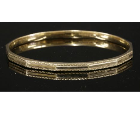 A 9ct gold Art Deco hollow slave bangle,by Cropp & Farr, with a series of flat facets with an engine turned border.  Birmingh