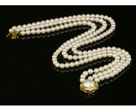 A three-row uniform cultured pearl choker,with an 18ct gold mabé pearl and diamond clasp.  Three rows of uniform cultured pea
