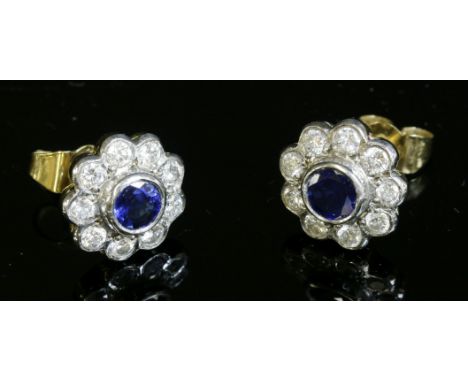 A pair of two-colour gold, sapphire and diamond daisy cluster earrings,a circular mixed cut sapphire, rub set to the centre, 