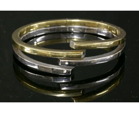 A two-colour gold hinged bangle,with two pairs of yellow and white hollow, square section, interlocking halves.  Signed 'Dama