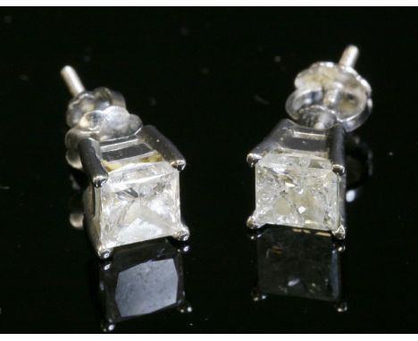 A pair of white gold single stone diamond stud earrings,with each princess cut diamond, four claw set to a plain collet.  Scr