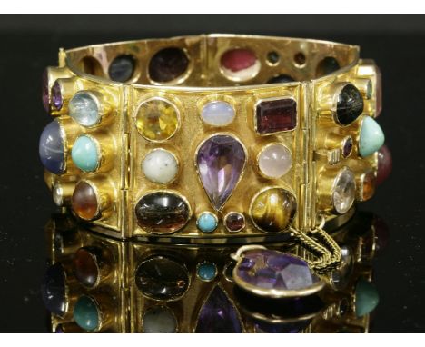 A specimen gemstone gold bracelet, c.1960,with a series of rectangular arched plaques.  Each plaque rub set with assorted cab