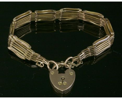An Edwardian gold, six-row, gate bracelet,with pairs of narrow interior links to wider, wavy, outer links and a large padlock