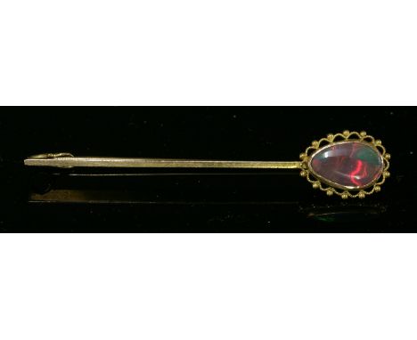 A single stone black opal bar brooch or tiepin, c.1915,with a pear-shaped cabochon black opal, rub set to one end, with a mil