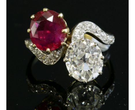 A two stone untreated Burma ruby and diamond crossover ring,with diamond set shoulders.  A slightly oval old European cut dia